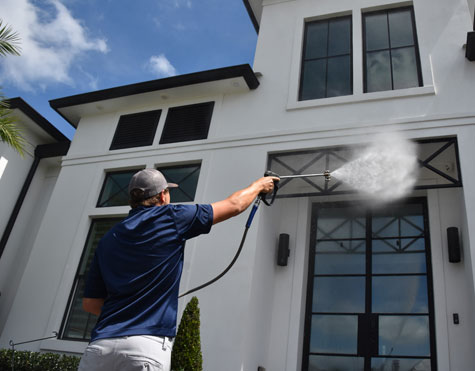 A man cleaning house while using pressure washer